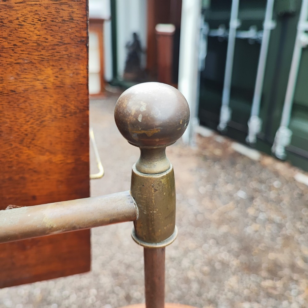 An antique Victorian adjustable mahogany reading stand featuring a revolving book rest with page holders, a secondary circular tray, and a telescopic brass stem on a cast iron base. View VIII