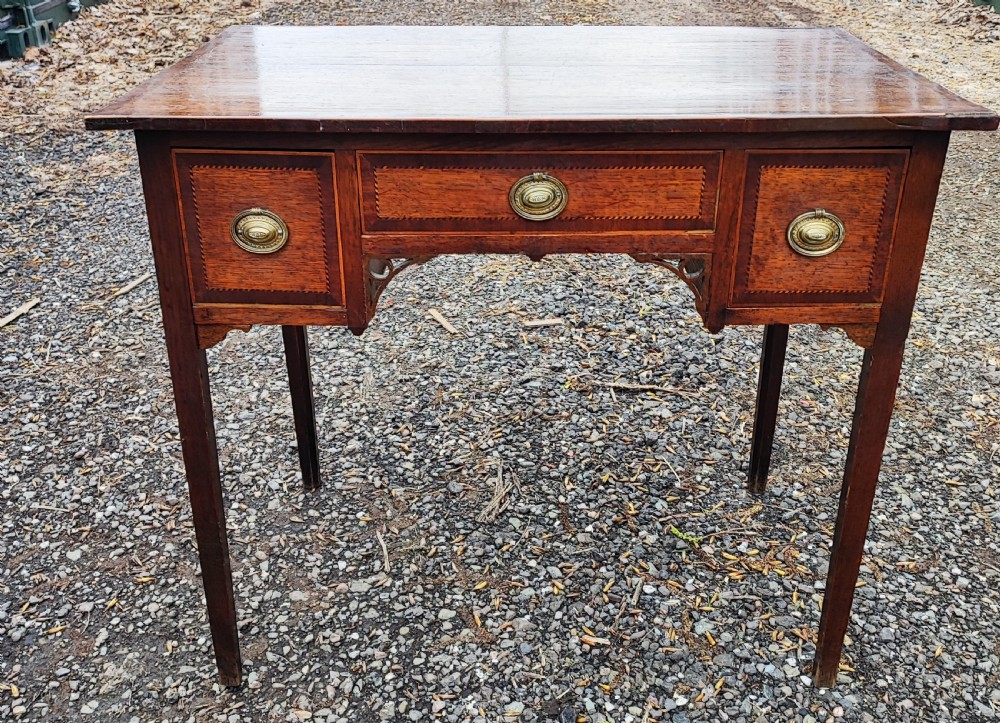 A Georgian dark oak lowboy side table featuring a rectangular top, three drawers with brass handles, inlaid stringing, corner spandrels, and straight tapering legs. View IX