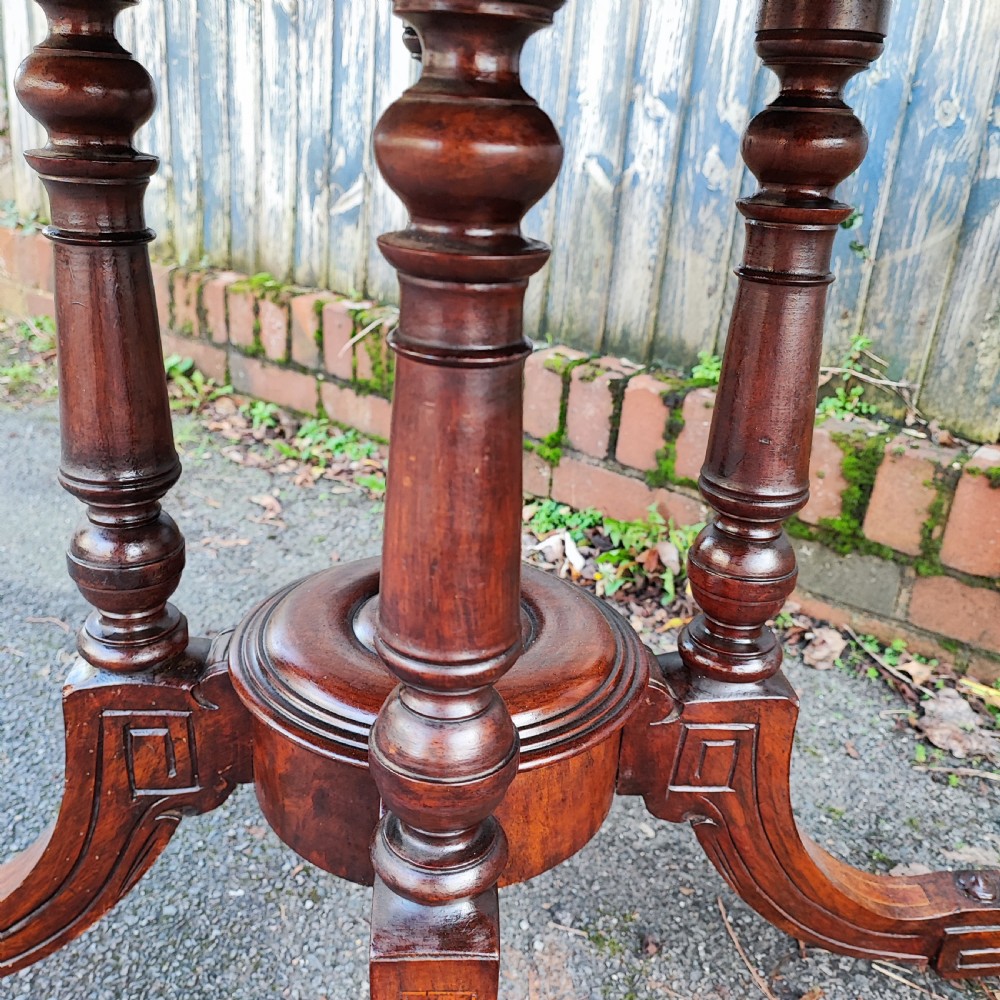 An octagonal Victorian centre table made of burr walnut featuring an inlaid floral marquetry border and a turned four-column pedestal base. View II