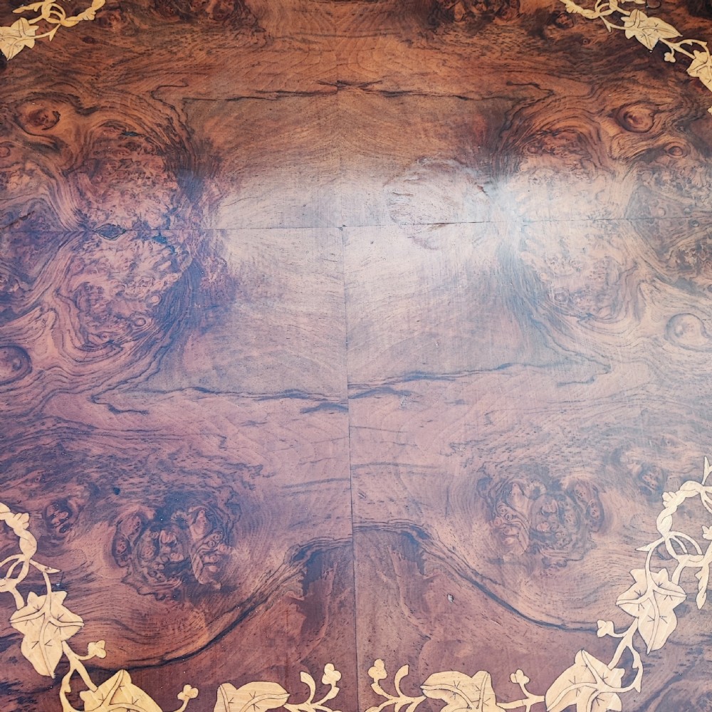 An octagonal Victorian centre table made of burr walnut featuring an inlaid floral marquetry border and a turned four-column pedestal base. View VII
