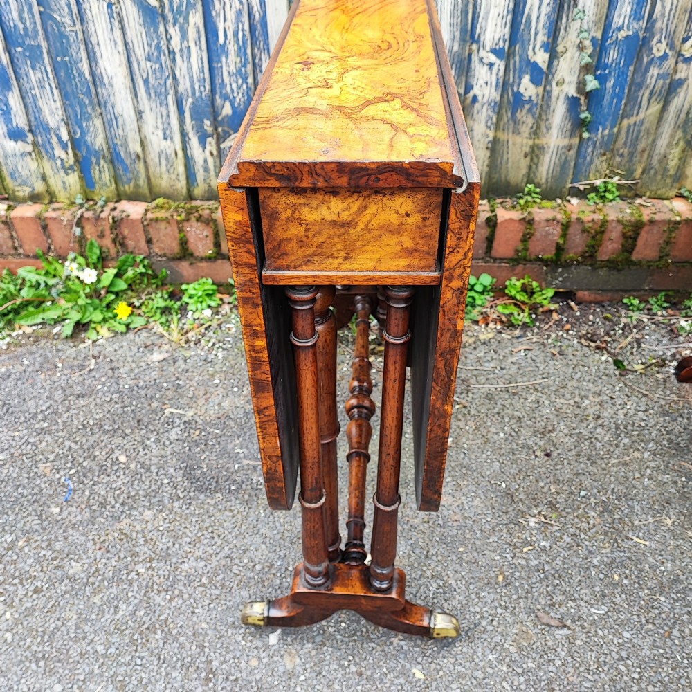 A Victorian burr walnut Sutherland table with extended drop leaves, turned twin-column supports, and brass castors. View IV