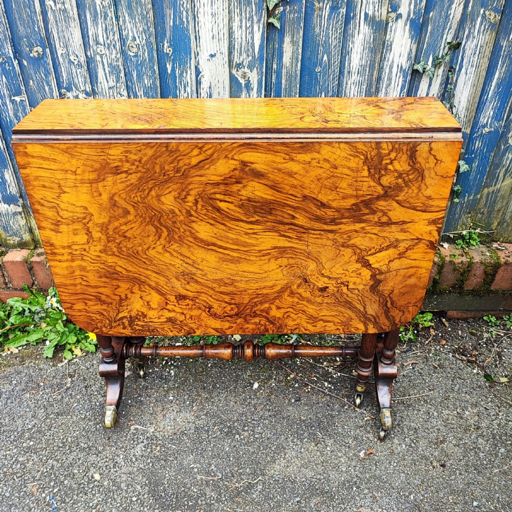 A Victorian burr walnut Sutherland table with extended drop leaves, turned twin-column supports, and brass castors. View IX