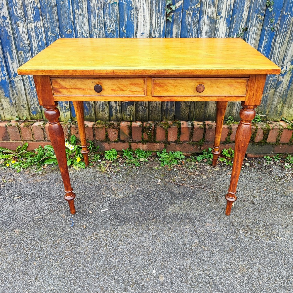 A golden satinwood side writing table featuring two frieze drawers with turned handles and four turned tapered legs. View VI