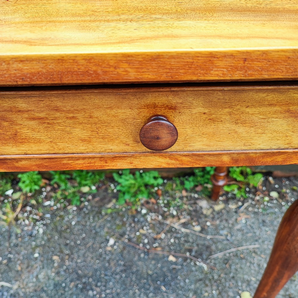 A golden satinwood side writing table featuring two frieze drawers with turned handles and four turned tapered legs. View VII