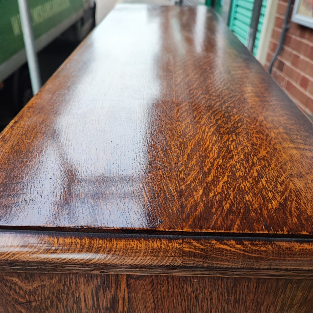 A warm brown oak Jacobean revival bookcase featuring double glazed doors with geometric diamond astragals, carved top frieze, and barley twist legs connected by a stretcher base. View II