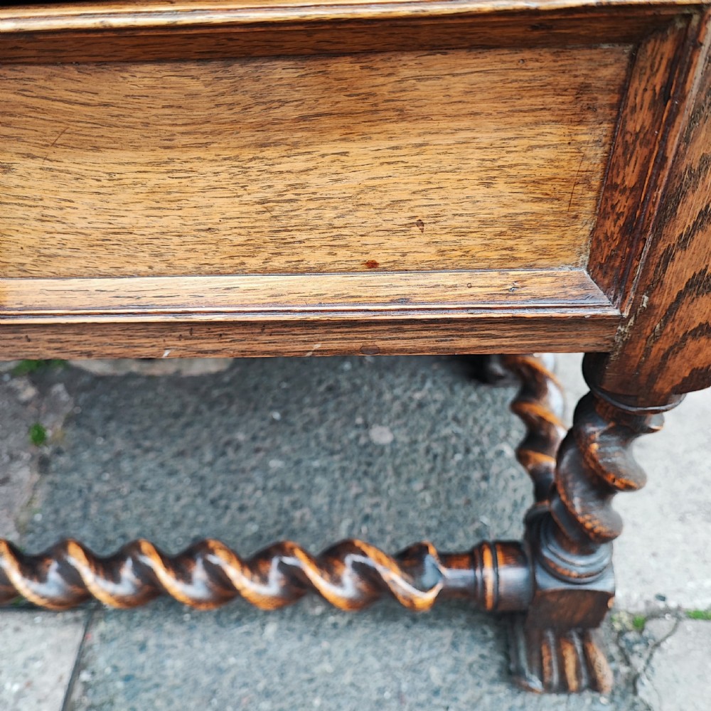 A warm brown oak Jacobean revival bookcase featuring double glazed doors with geometric diamond astragals, carved top frieze, and barley twist legs connected by a stretcher base. View IX