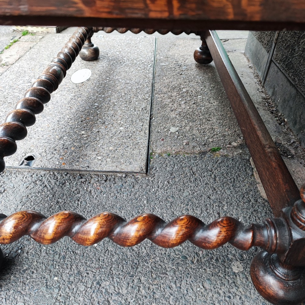 A Jacobean style oak bureau with geometric panelled drawers, a slant front writing lid, brass teardrop handles, and barley twist legs with a matching stretcher. View II