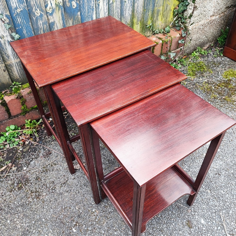 A set of three graduated Edwardian mahogany nesting tables with rectangular tops and slender square legs. View V