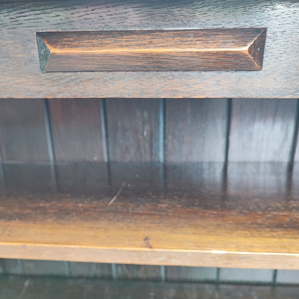 A dark oak open bookcase featuring five horizontal shelves, a scalloped upper frieze, vertical panelled backboards, and rounded bun feet. View IV