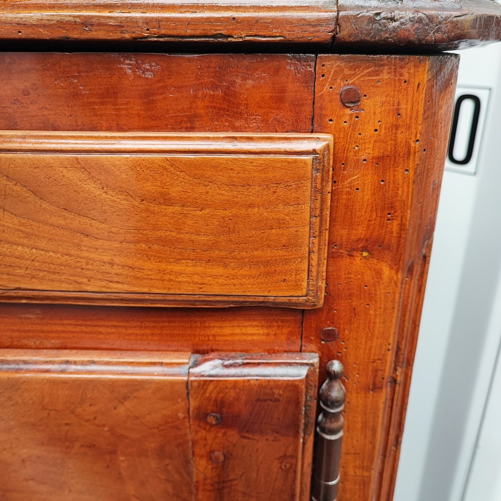 An 18th century French cherry wood side cabinet featuring two drawers above two carved panel doors with ornate metal escutcheons and cabriole feet. View X