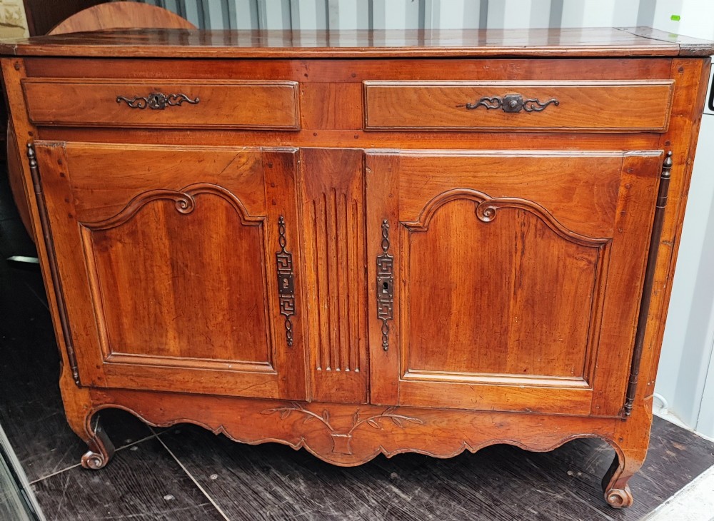 An 18th century French cherry wood side cabinet featuring two drawers above two carved panel doors with ornate metal escutcheons and cabriole feet. View XIII
