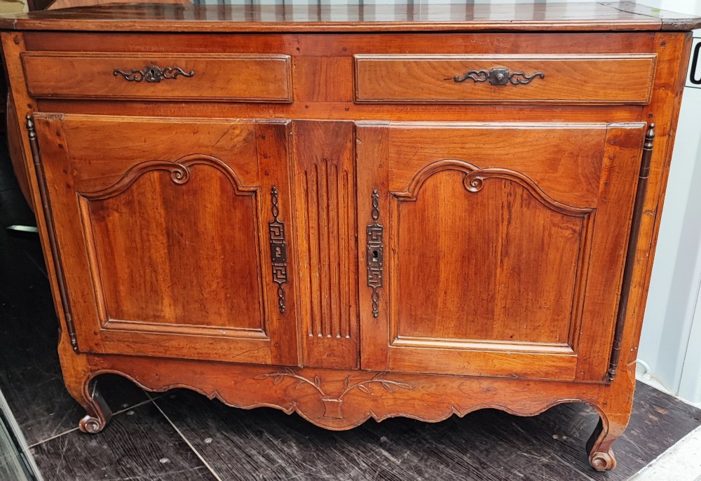 An 18th century French cherry wood side cabinet featuring two drawers above two carved panel doors with ornate metal escutcheons and cabriole feet. View XIV