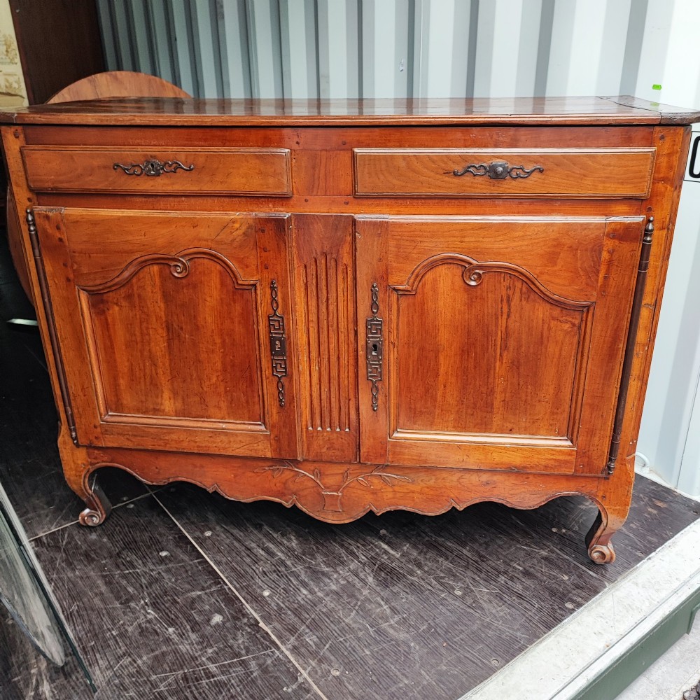An 18th century French cherry wood side cabinet featuring two drawers above two carved panel doors with ornate metal escutcheons and cabriole feet. View XV