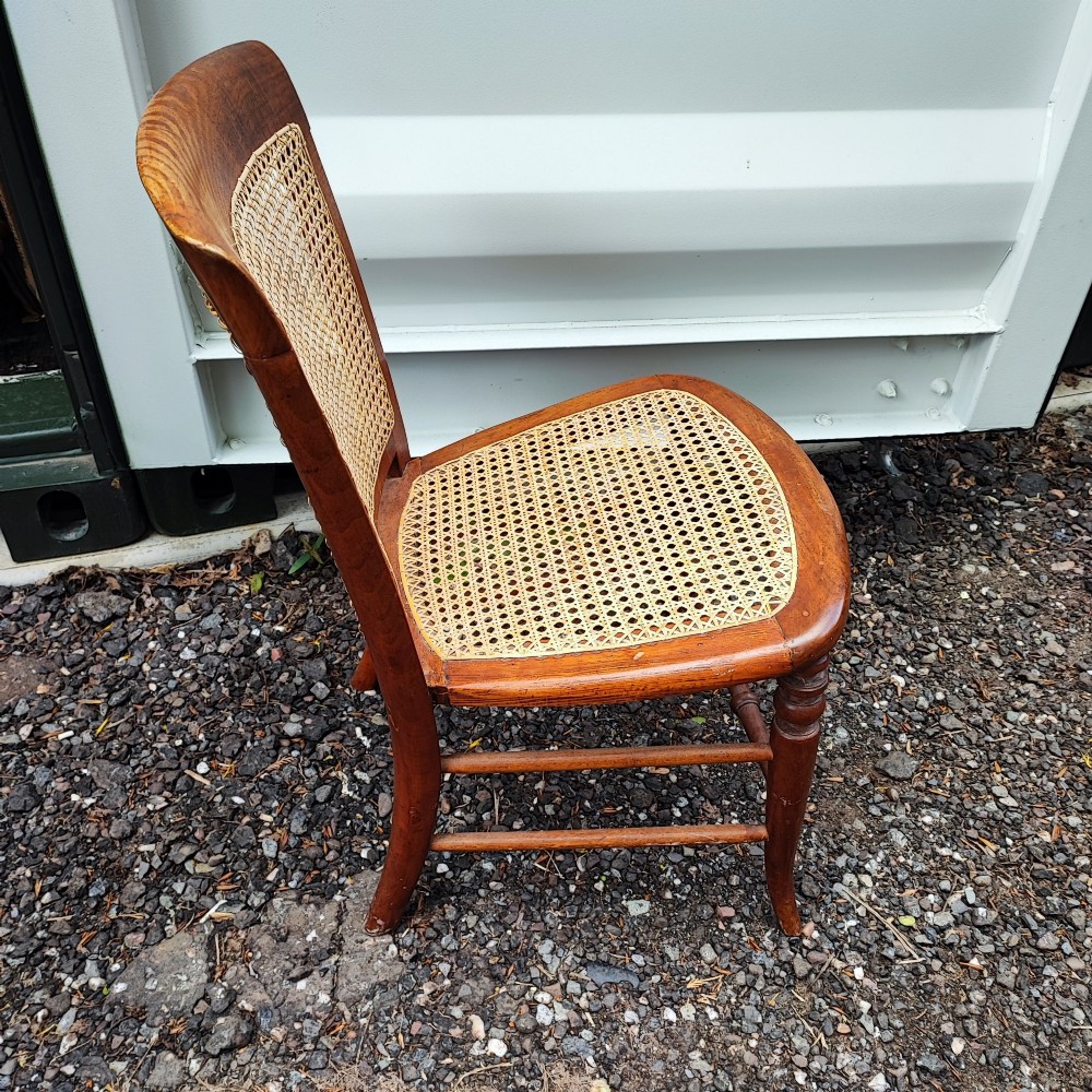 An antique mahogany chair featuring a curved backrest, turned front legs, and woven cane panels set into the seat and back. View II