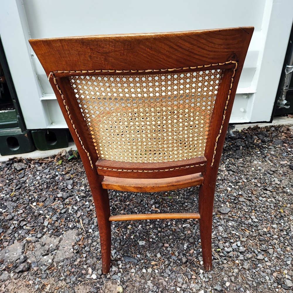 An antique mahogany chair featuring a curved backrest, turned front legs, and woven cane panels set into the seat and back. View III