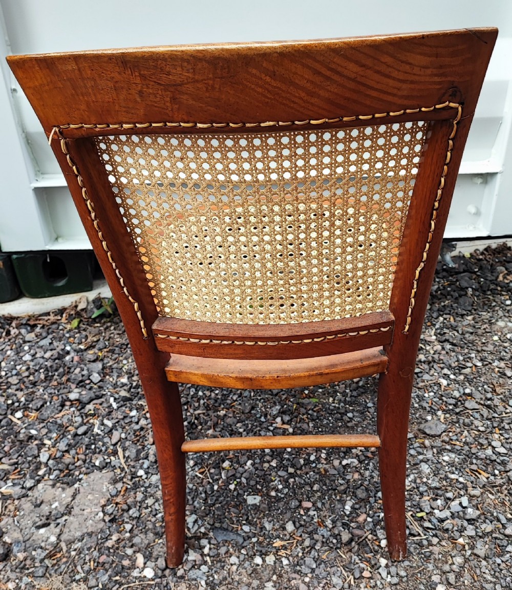 An antique mahogany chair featuring a curved backrest, turned front legs, and woven cane panels set into the seat and back. View IV