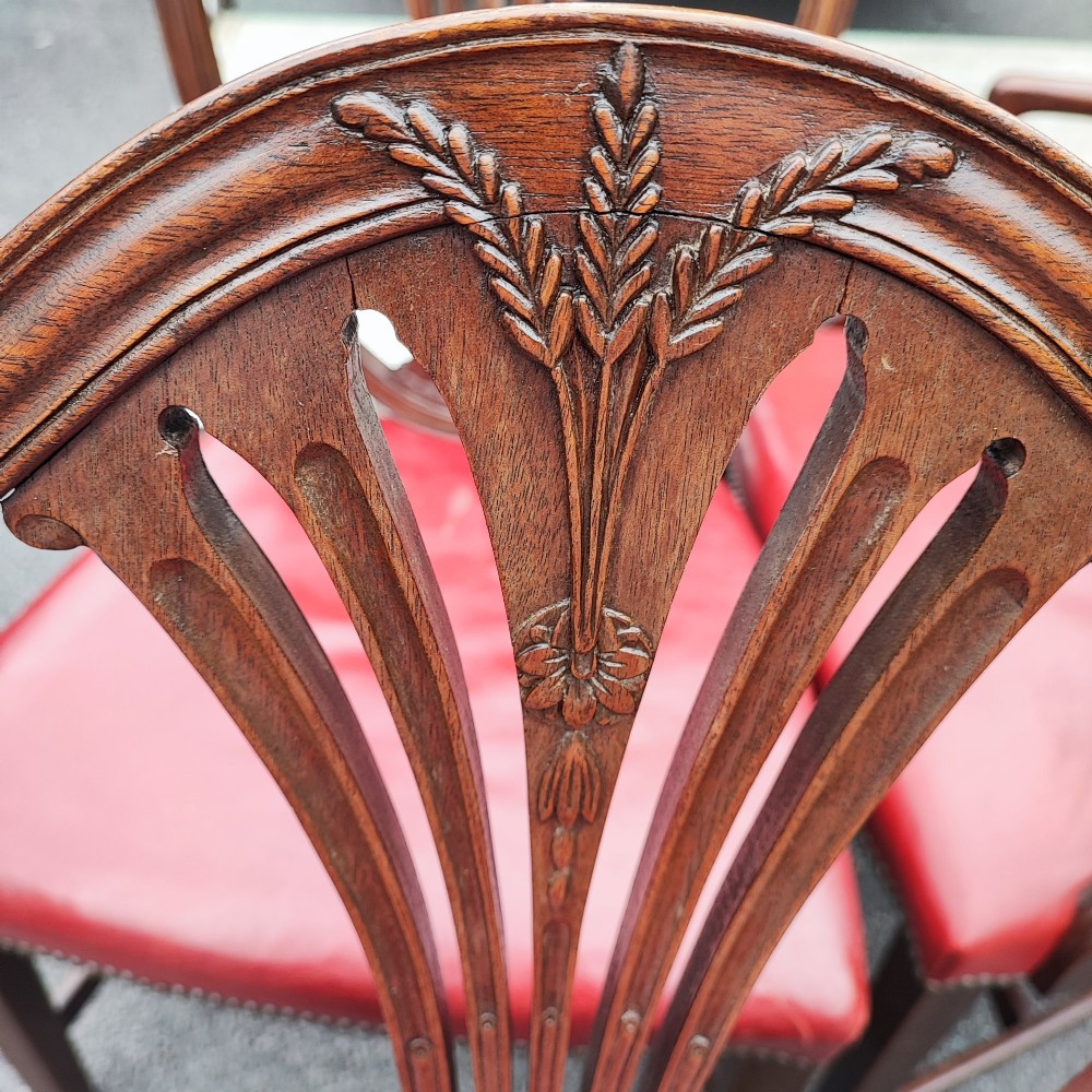 A set of eight mahogany Georgian-style dining chairs featuring carved wheat sheaf shield backs and red leather seats. View II