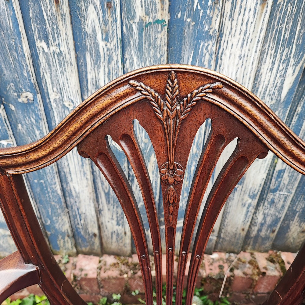 A set of eight mahogany Georgian-style dining chairs featuring carved wheat sheaf shield backs and red leather seats. View V