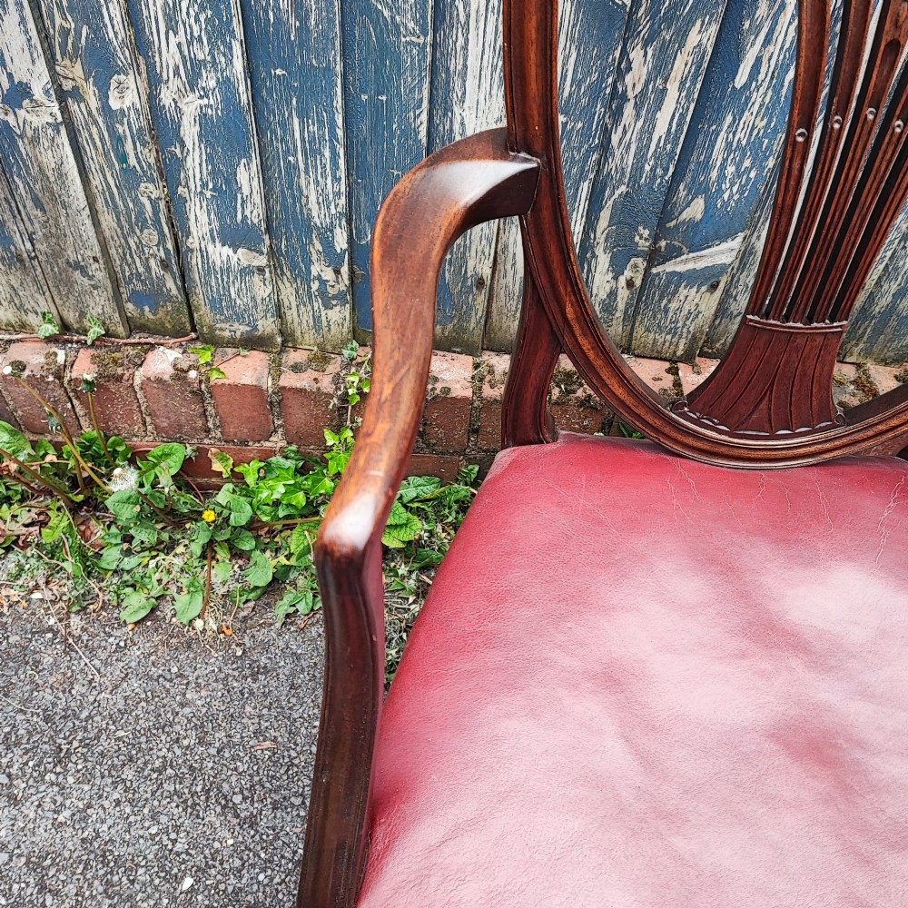 A set of eight mahogany Georgian-style dining chairs featuring carved wheat sheaf shield backs and red leather seats. View VIII