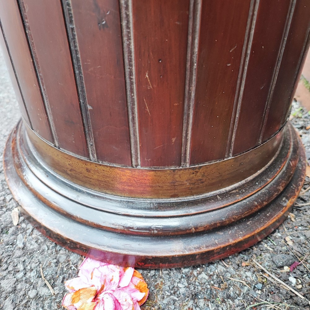 A cylindrical dark mahogany umbrella stand featuring three brass binding hoops, side ring handles, and a moulded circular base. View V
