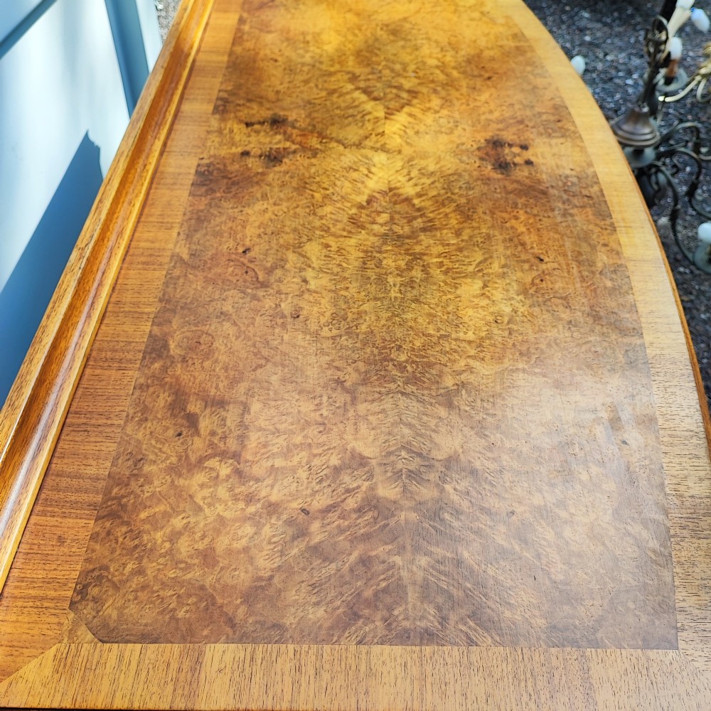 An antique burr walnut writing table featuring five drawers, brass handles, and carved cabriole legs. View II