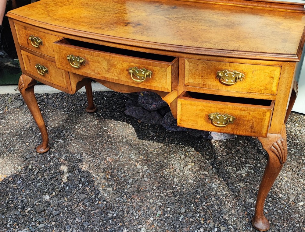 An antique burr walnut writing table featuring five drawers, brass handles, and carved cabriole legs. View V