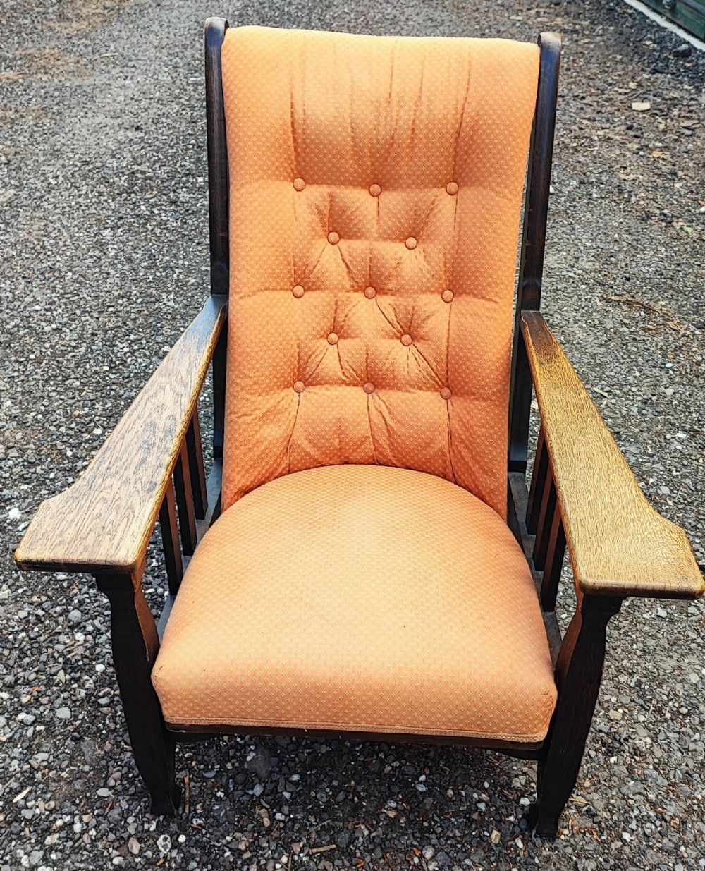 An antique Arts and Crafts oak reclining armchair with broad flat armrests, slatted sides, and orange buttoned upholstery. View IV