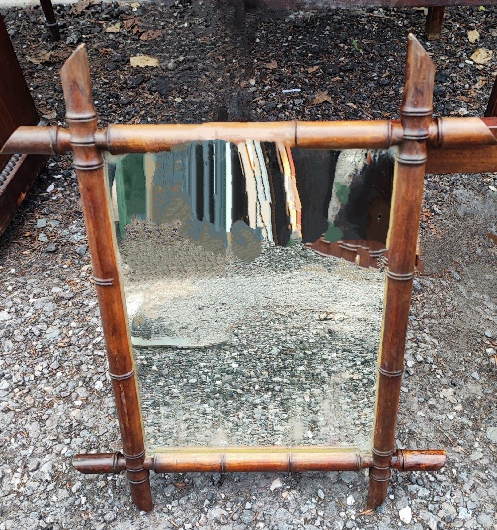 An antique French faux bamboo wall mirror featuring a rectangular warm brown wooden frame carved to imitate bamboo stalks with crossed joinery.