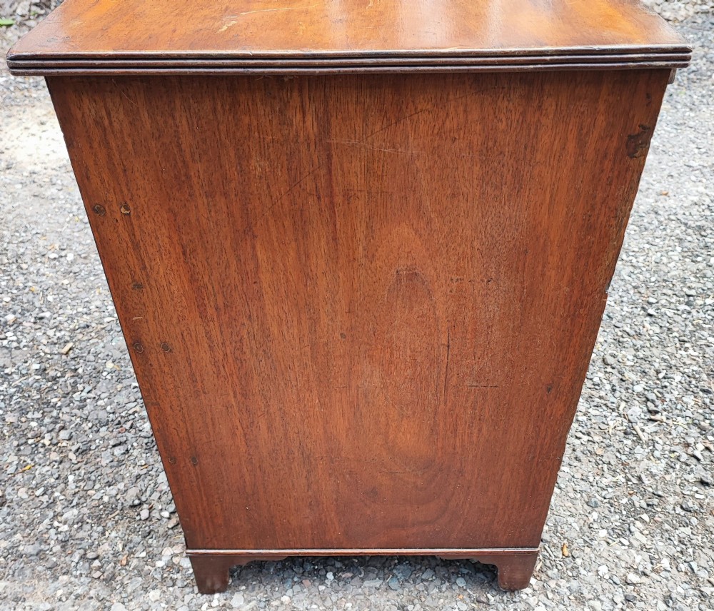 An antique Regency mahogany chest of drawers featuring four full-width drawers with brass oval handles and bracket feet. View V