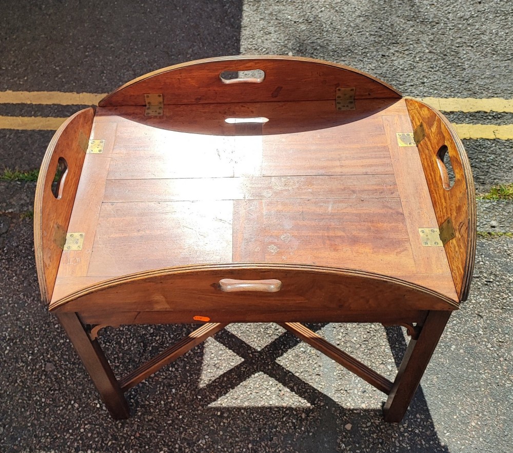 An antique mahogany campaign tray table featuring four hinged drop-down gallery sides with cutout carry handles and brass fittings, supported on a matching wooden stand.