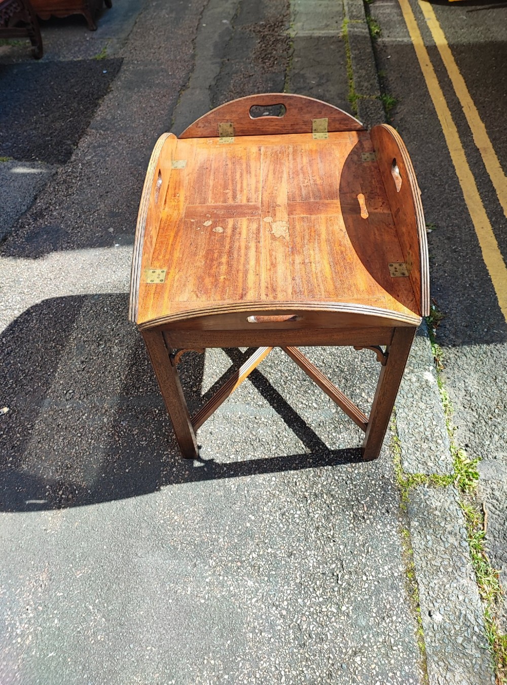 An antique mahogany campaign tray table featuring four hinged drop-down gallery sides with cutout carry handles and brass fittings, supported on a matching wooden stand. View III
