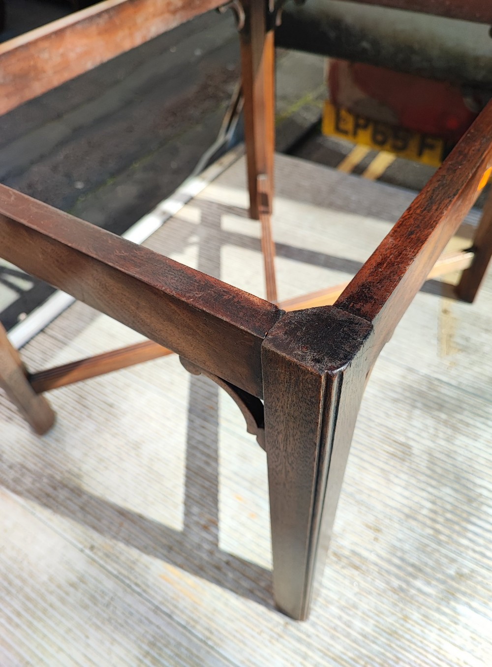 An antique mahogany campaign tray table featuring four hinged drop-down gallery sides with cutout carry handles and brass fittings, supported on a matching wooden stand. View V