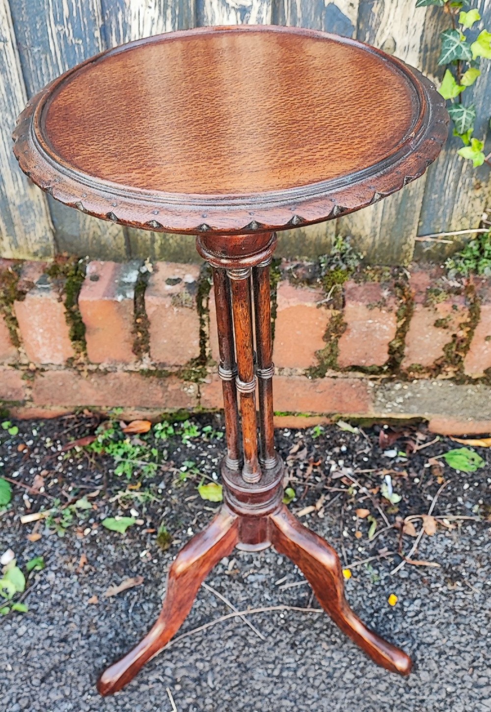 An antique mahogany wine table featuring a dished circular top, a turned cluster column stem, and three curved tripod legs.