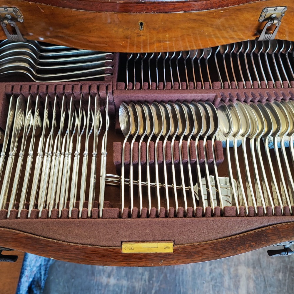 An open burr walnut cutlery canteen table featuring two fitted drawers containing rows of silver-plated flatware. View II