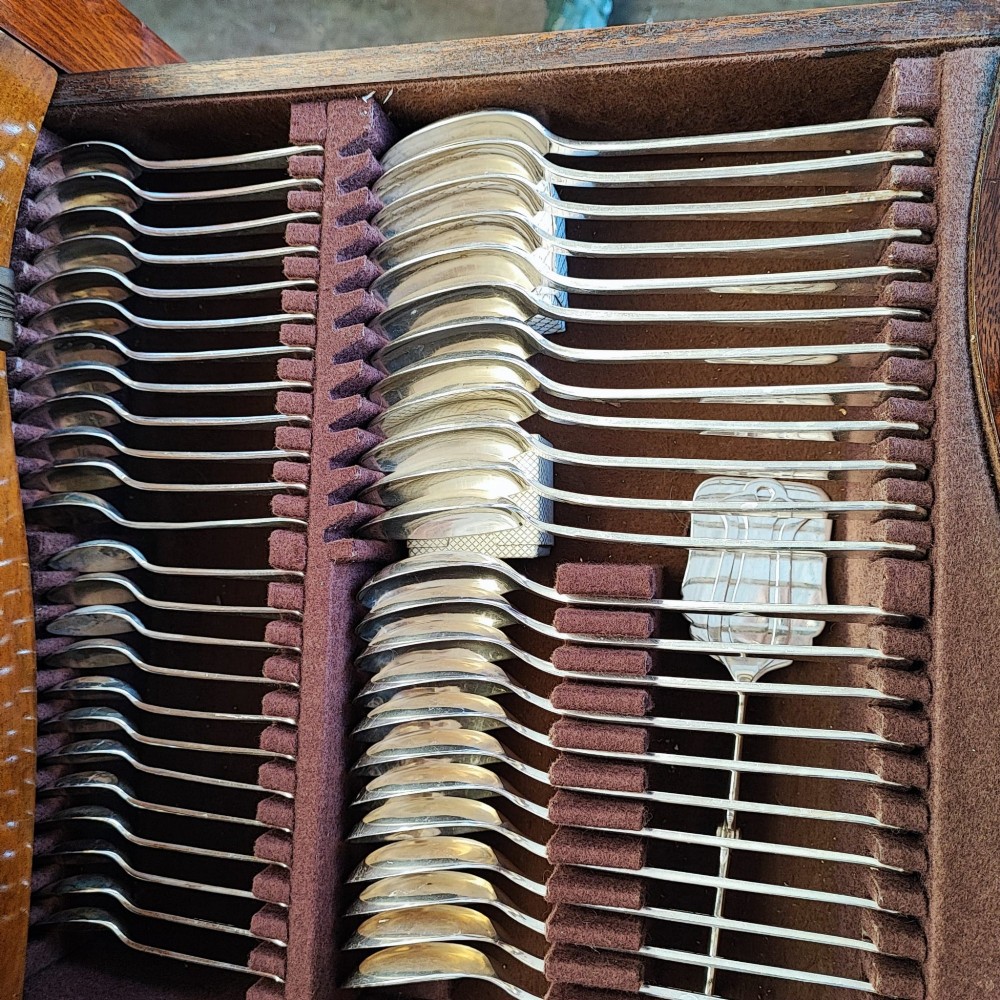 An open burr walnut cutlery canteen table featuring two fitted drawers containing rows of silver-plated flatware. View III