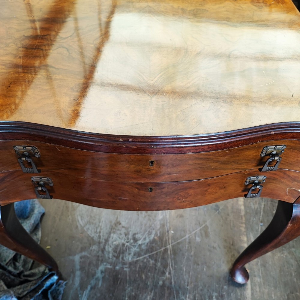 An open burr walnut cutlery canteen table featuring two fitted drawers containing rows of silver-plated flatware. View V