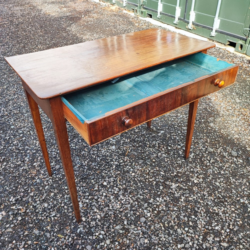 A Georgian mahogany side table with square tapered legs and an open single drawer featuring green lining paper and turned wooden knobs.