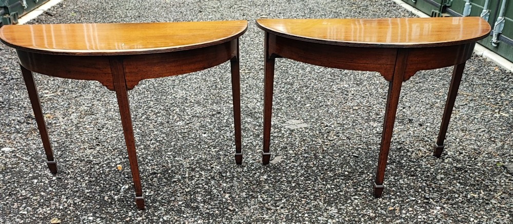 A pair of Georgian demi lune mahogany console tables