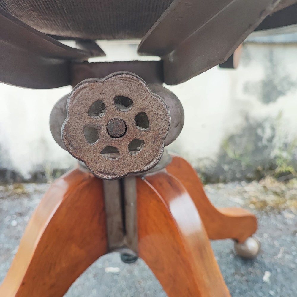 An antique mahogany revolving desk chair featuring a curved slatted back, studded leather seat, and a quadruped swivel base on castors. View VI