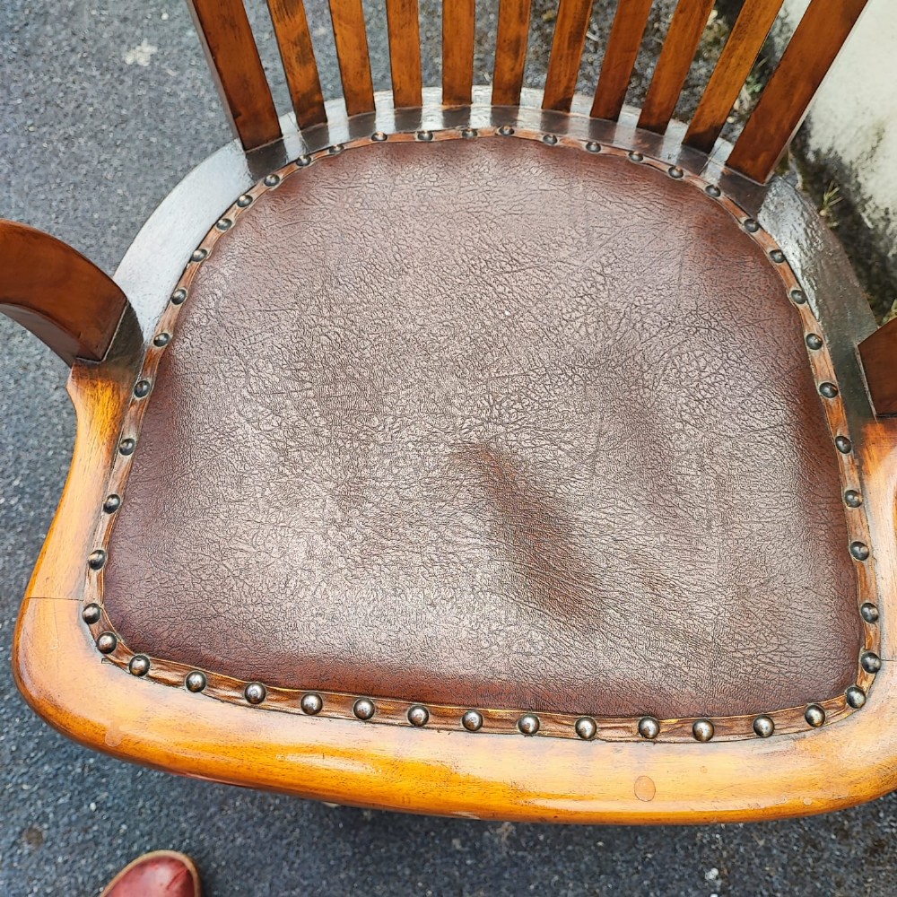 An antique mahogany revolving desk chair featuring a curved slatted back, studded leather seat, and a quadruped swivel base on castors. View VIII