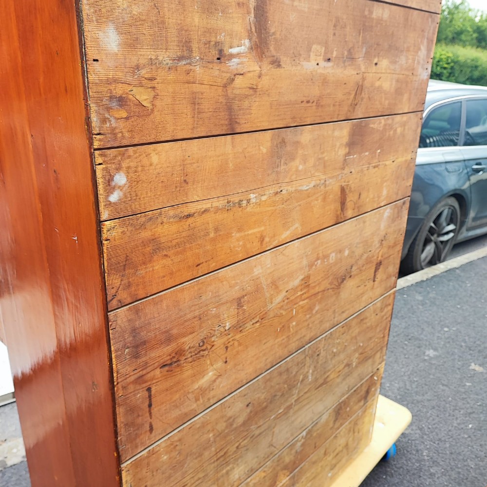 A tall antique pine chest of drawers featuring eight drawers with brass drop handles and a natural honey wood grain. View II