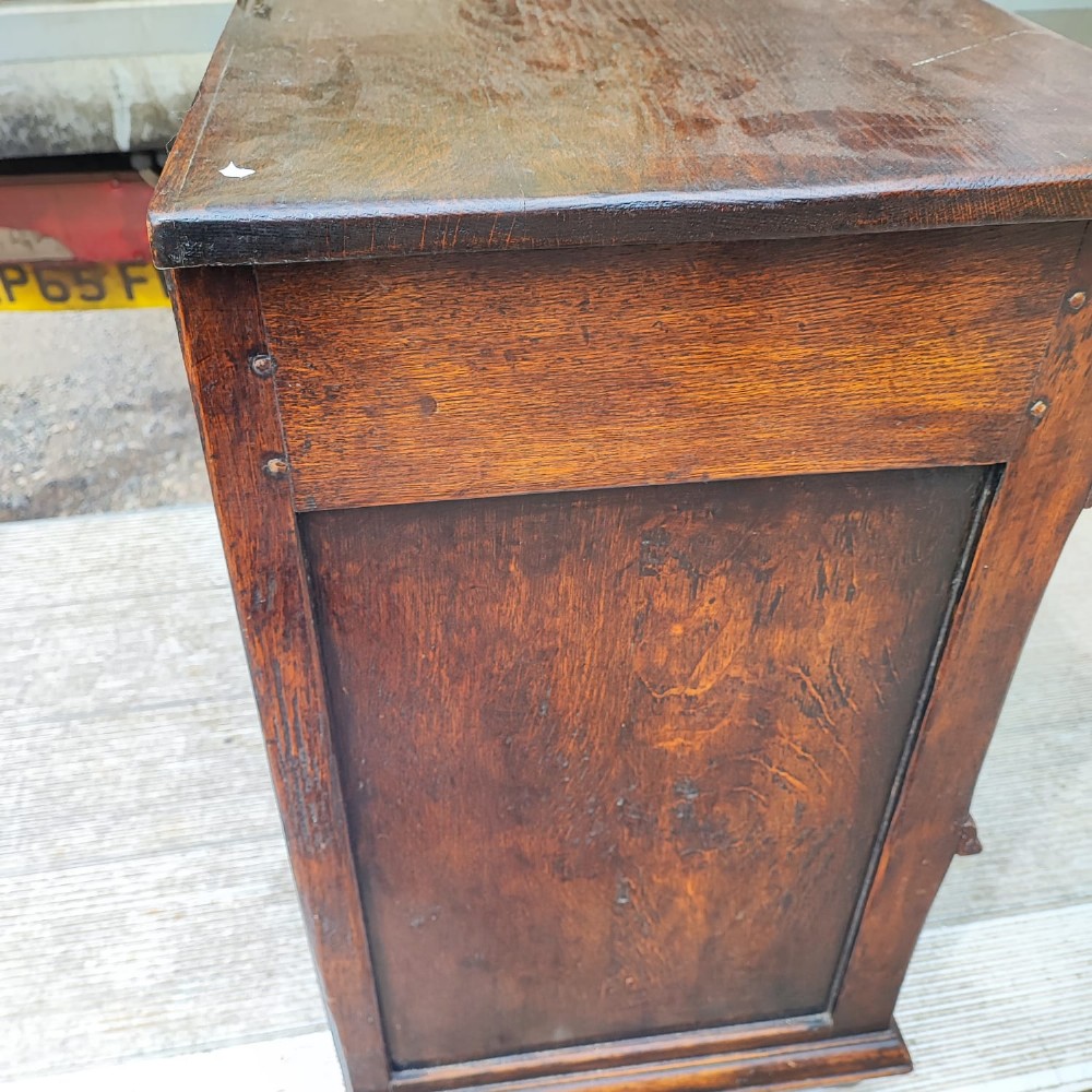 A dark oak Jacobean chest of drawers featuring geometric panel moulding, a carved top drawer, and brass drop handles. View II