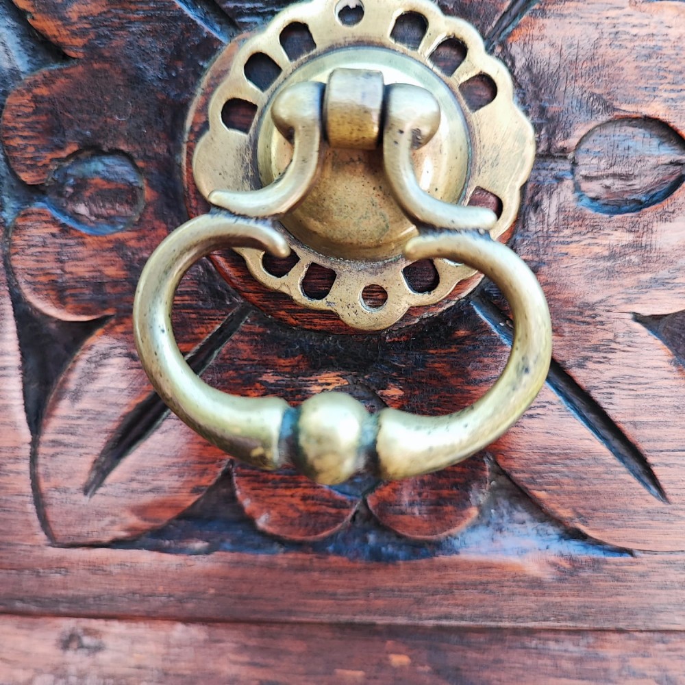 A dark oak Jacobean chest of drawers featuring geometric panel moulding, a carved top drawer, and brass drop handles. View VII