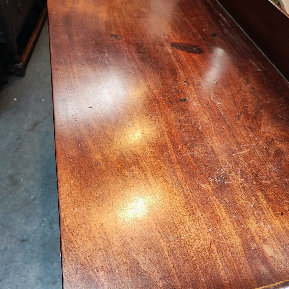 A Regency mahogany writing table featuring five drawers with circular brass backplates, a gallery back, an arched kneehole, and ring-turned legs. View II