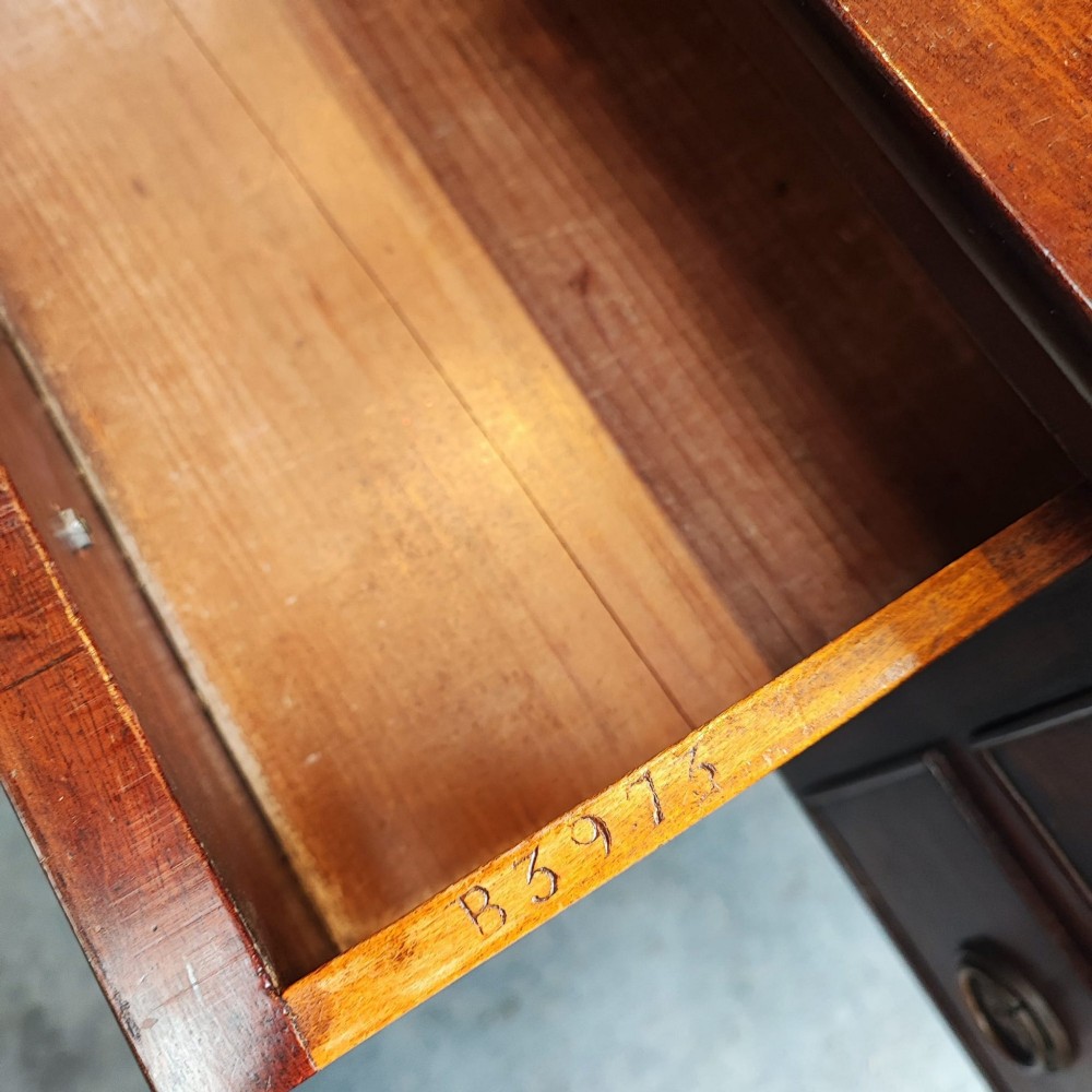 A Regency mahogany writing table featuring five drawers with circular brass backplates, a gallery back, an arched kneehole, and ring-turned legs. View IV