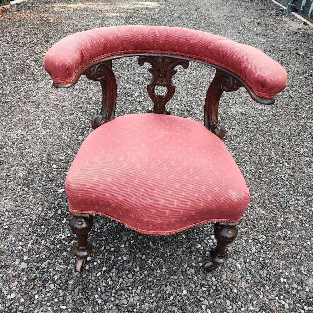 A Victorian mahogany desk chair featuring a padded red horseshoe backrest, carved central splat, and turned legs with castors. View II