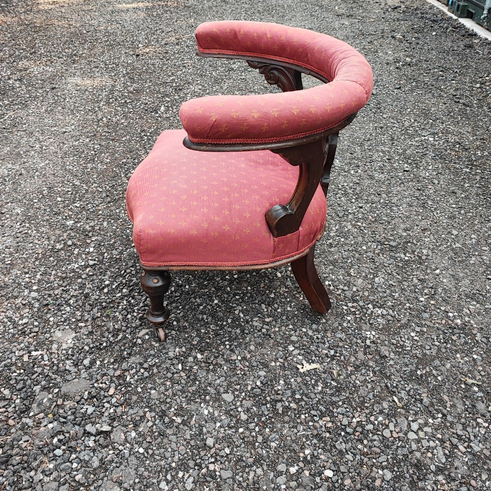 A Victorian mahogany desk chair featuring a padded red horseshoe backrest, carved central splat, and turned legs with castors. View III