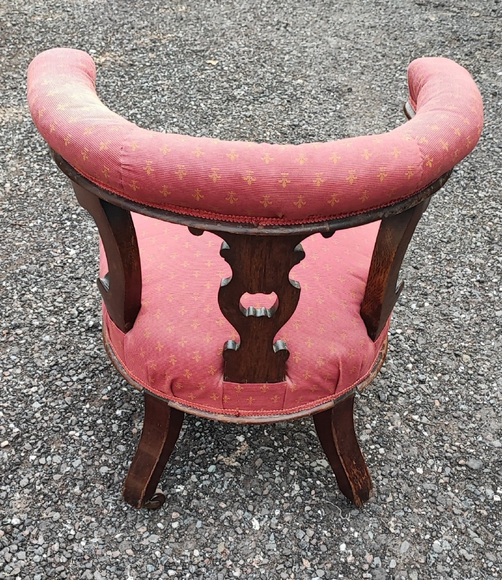 A Victorian mahogany desk chair featuring a padded red horseshoe backrest, carved central splat, and turned legs with castors. View IV