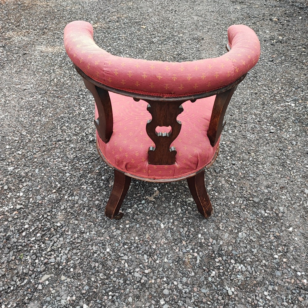 A Victorian mahogany desk chair featuring a padded red horseshoe backrest, carved central splat, and turned legs with castors. View VI