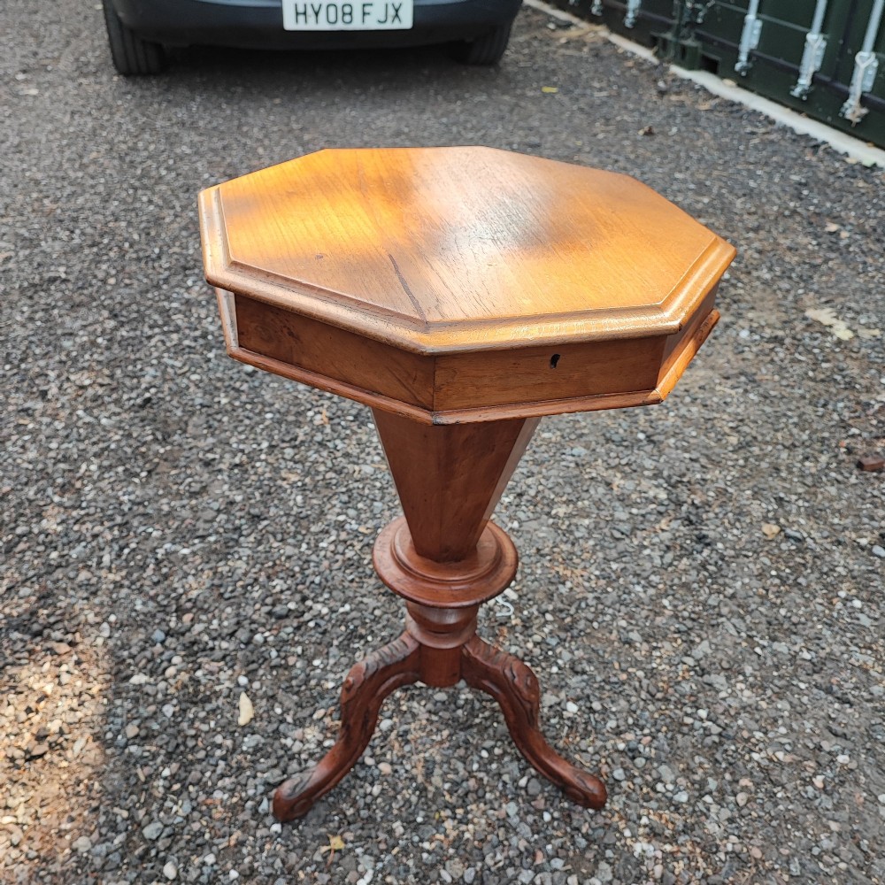 A Victorian walnut trumpet work box featuring an octagonal hinged top, tapering conical body, and carved tripod cabriole legs.